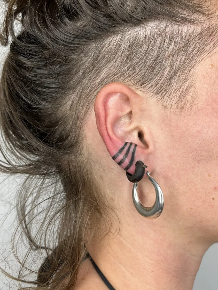 Tatouage handpoke ornemental autour de l’oreille, réalisé par Flori Green
