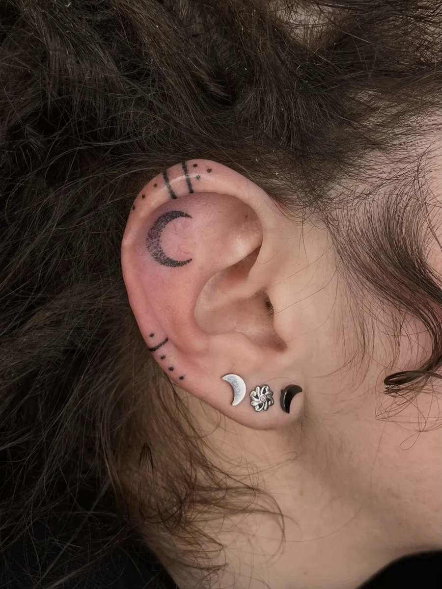 Tatouage handpoke ornemental autour de l’oreille, réalisé par Flori Green