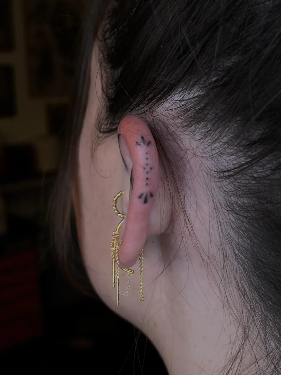 Tatouage handpoke ornemental autour de l’oreille, réalisé par Flori Green