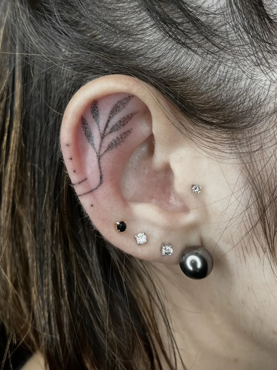 Tatouage handpoke ornemental autour de l’oreille, réalisé par Flori Green