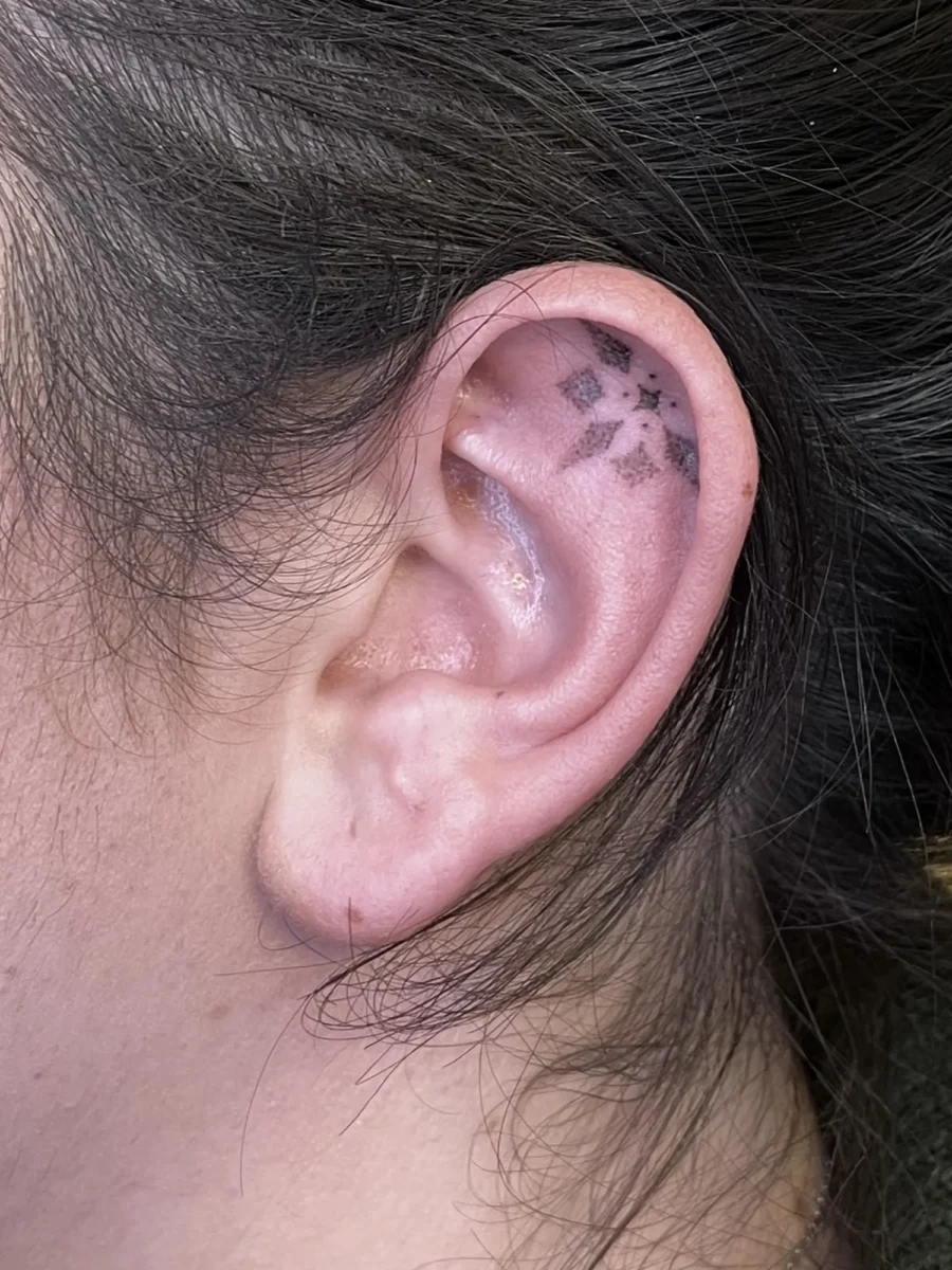 Tatouage handpoke ornemental autour de l’oreille, réalisé par Flori Green