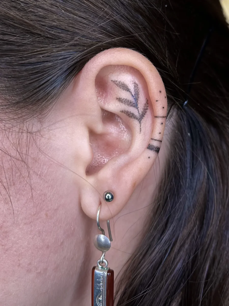 Tatouage handpoke ornemental autour de l’oreille, réalisé par Flori Green