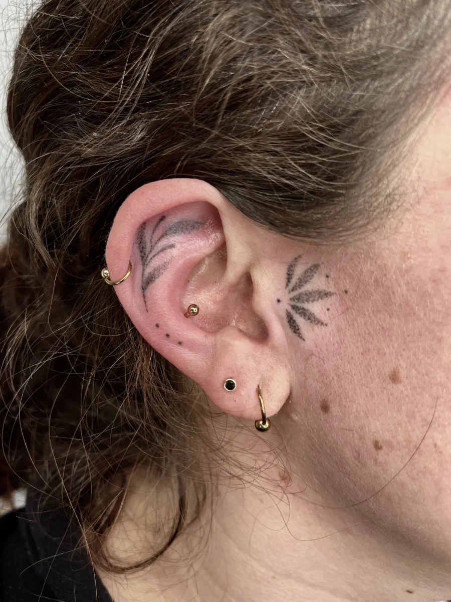 Tatouage handpoke ornemental autour de l’oreille, réalisé par Flori Green
