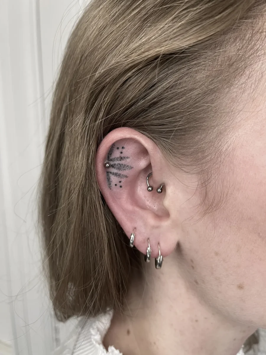 Tatouage handpoke ornemental autour de l’oreille, réalisé par Flori Green