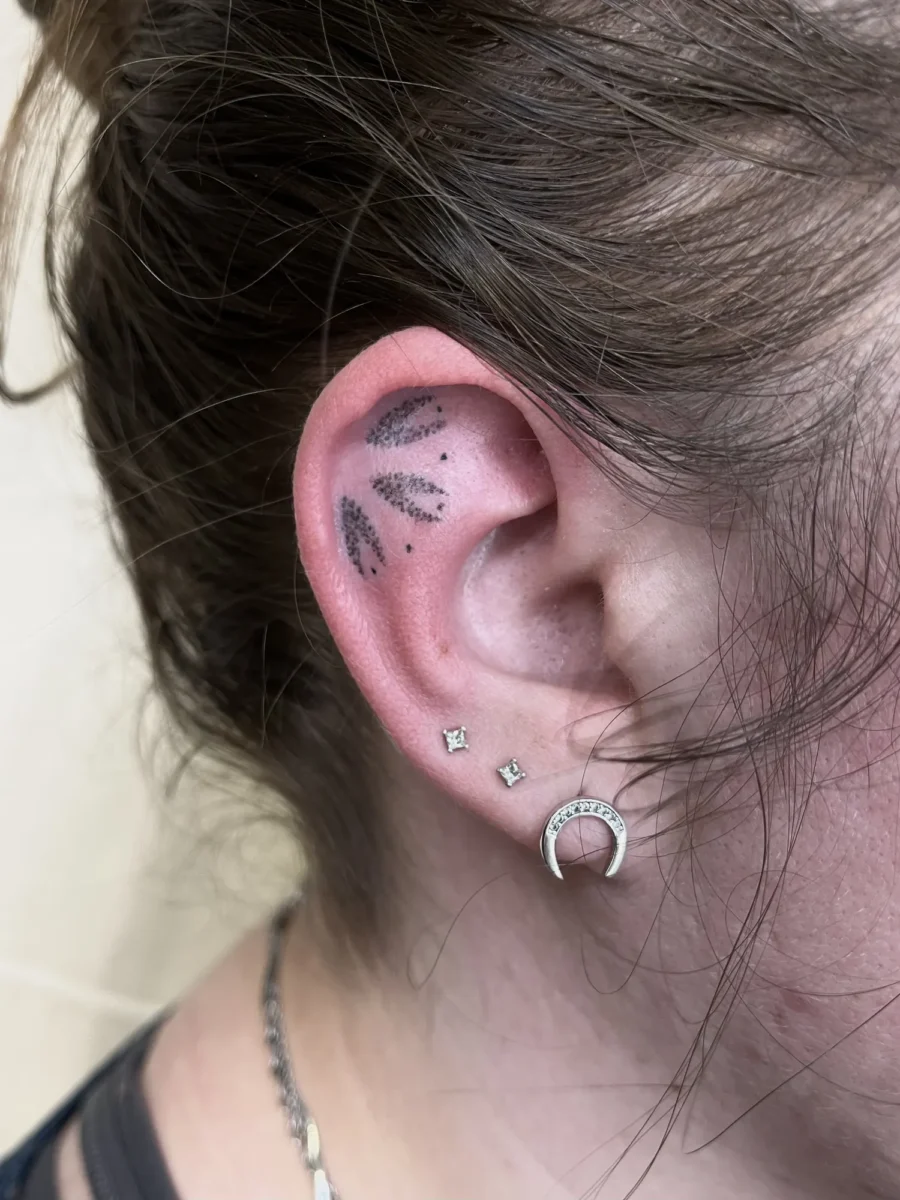 Tatouage handpoke ornemental autour de l’oreille, réalisé par Flori Green