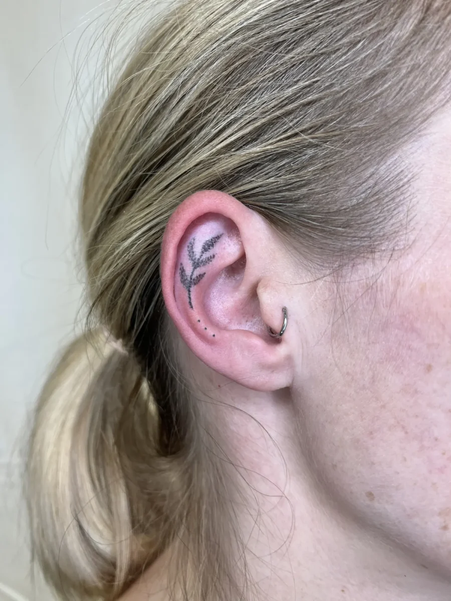 Tatouage handpoke ornemental autour de l’oreille, réalisé par Flori Green