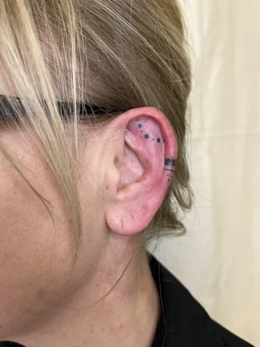 Tatouage handpoke ornemental autour de l’oreille, réalisé par Flori Green