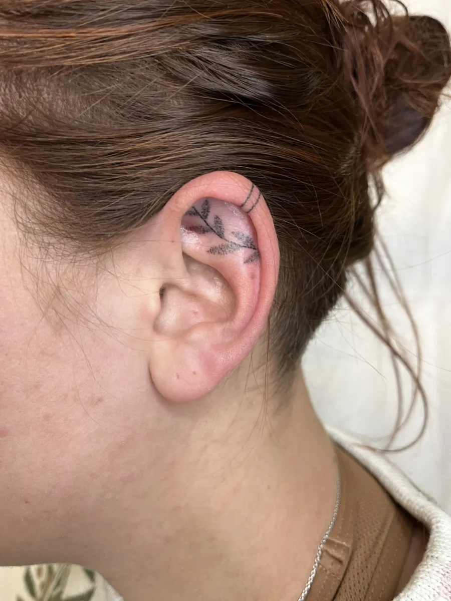 Tatouage handpoke ornemental autour de l’oreille, réalisé par Flori Green