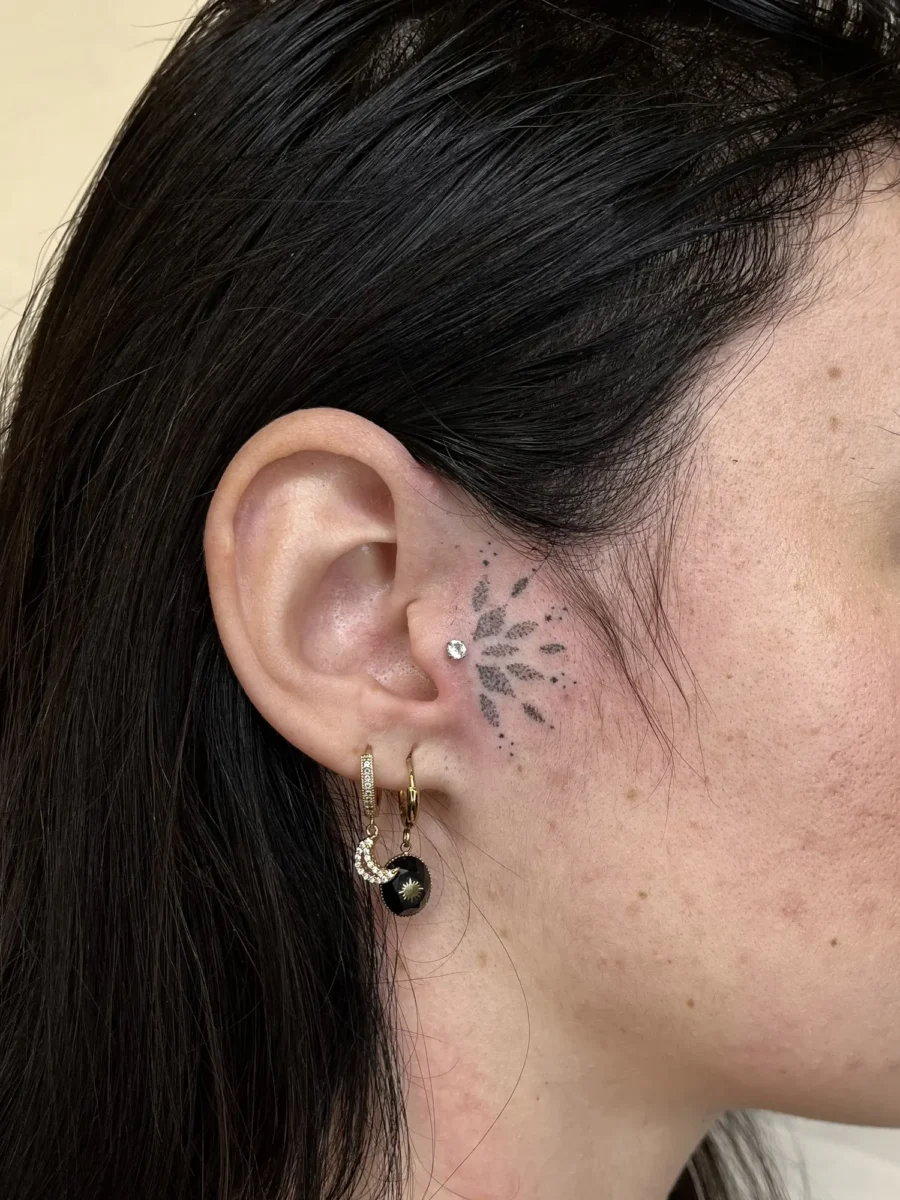 Tatouage handpoke ornemental autour de l’oreille, réalisé par Flori Green