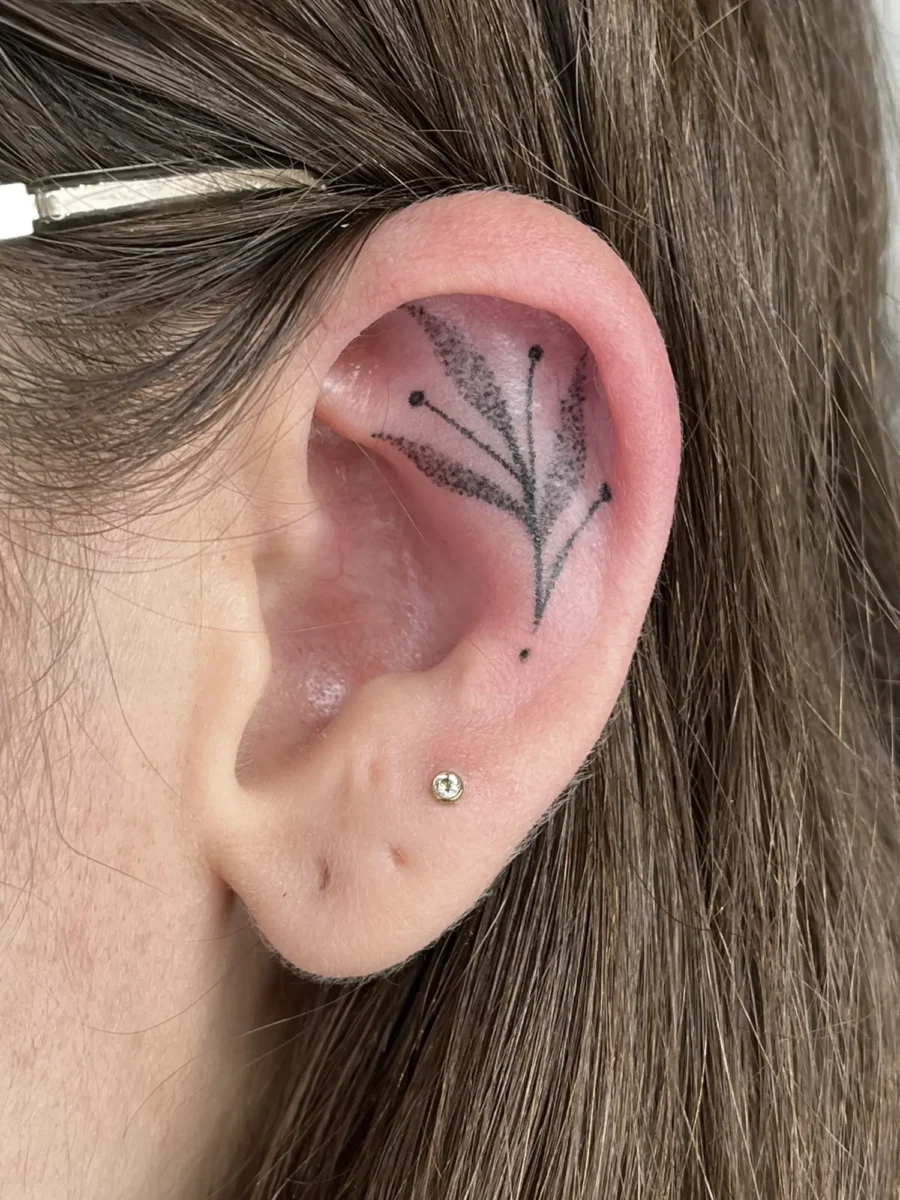 Tatouage handpoke ornemental autour de l’oreille, réalisé par Flori Green