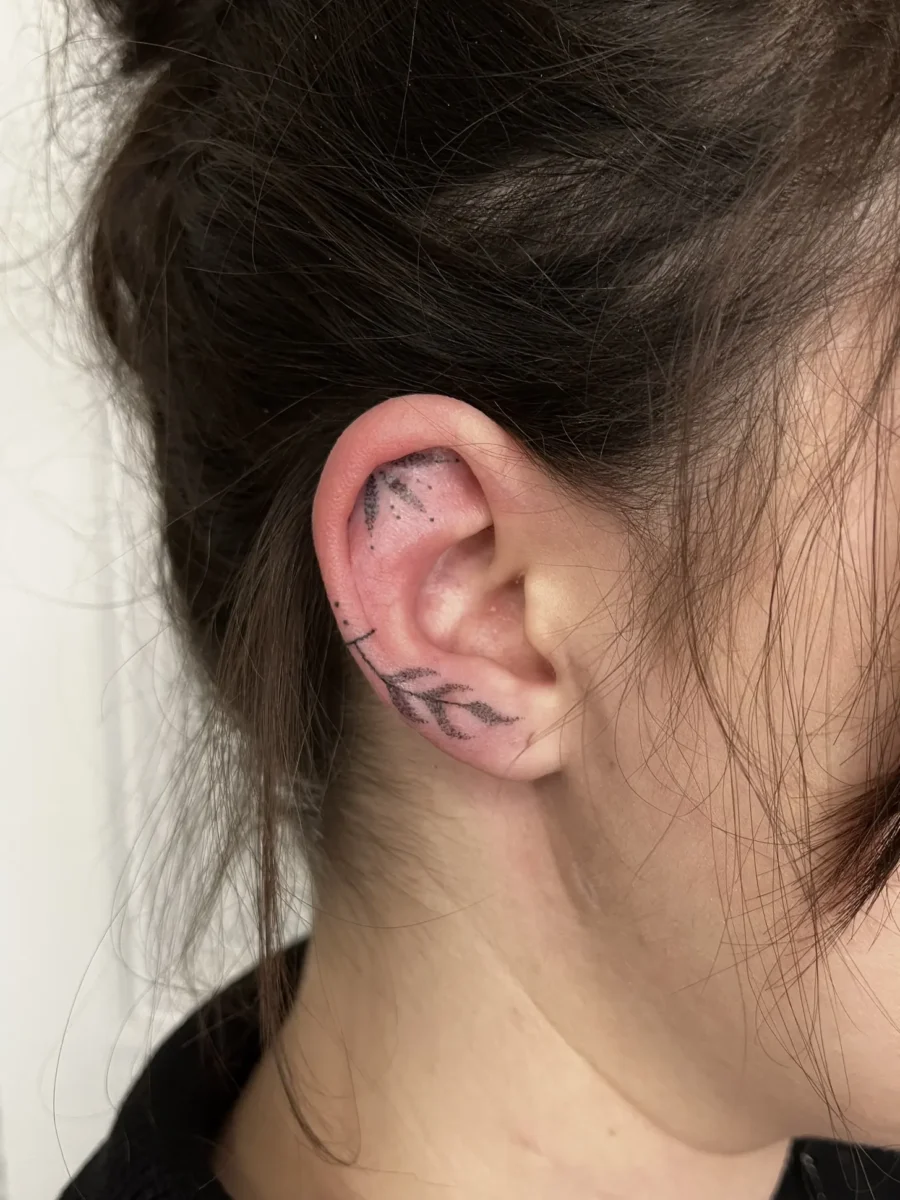 Tatouage handpoke ornemental autour de l’oreille, réalisé par Flori Green