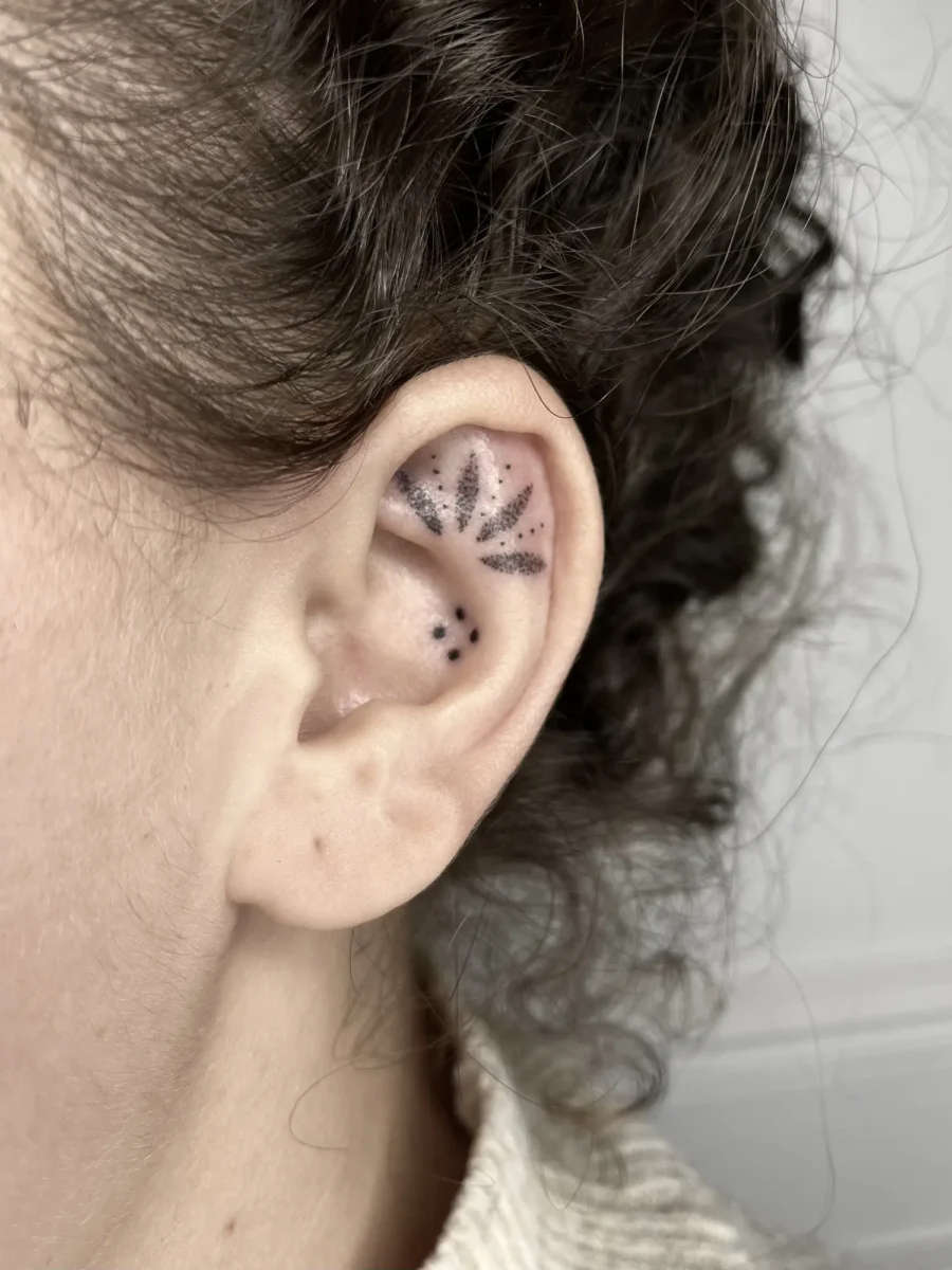 Tatouage handpoke ornemental autour de l’oreille, réalisé par Flori Green