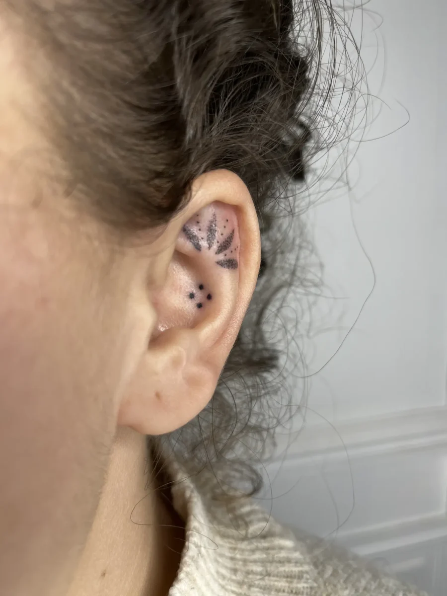 Tatouage handpoke ornemental autour de l’oreille, réalisé par Flori Green