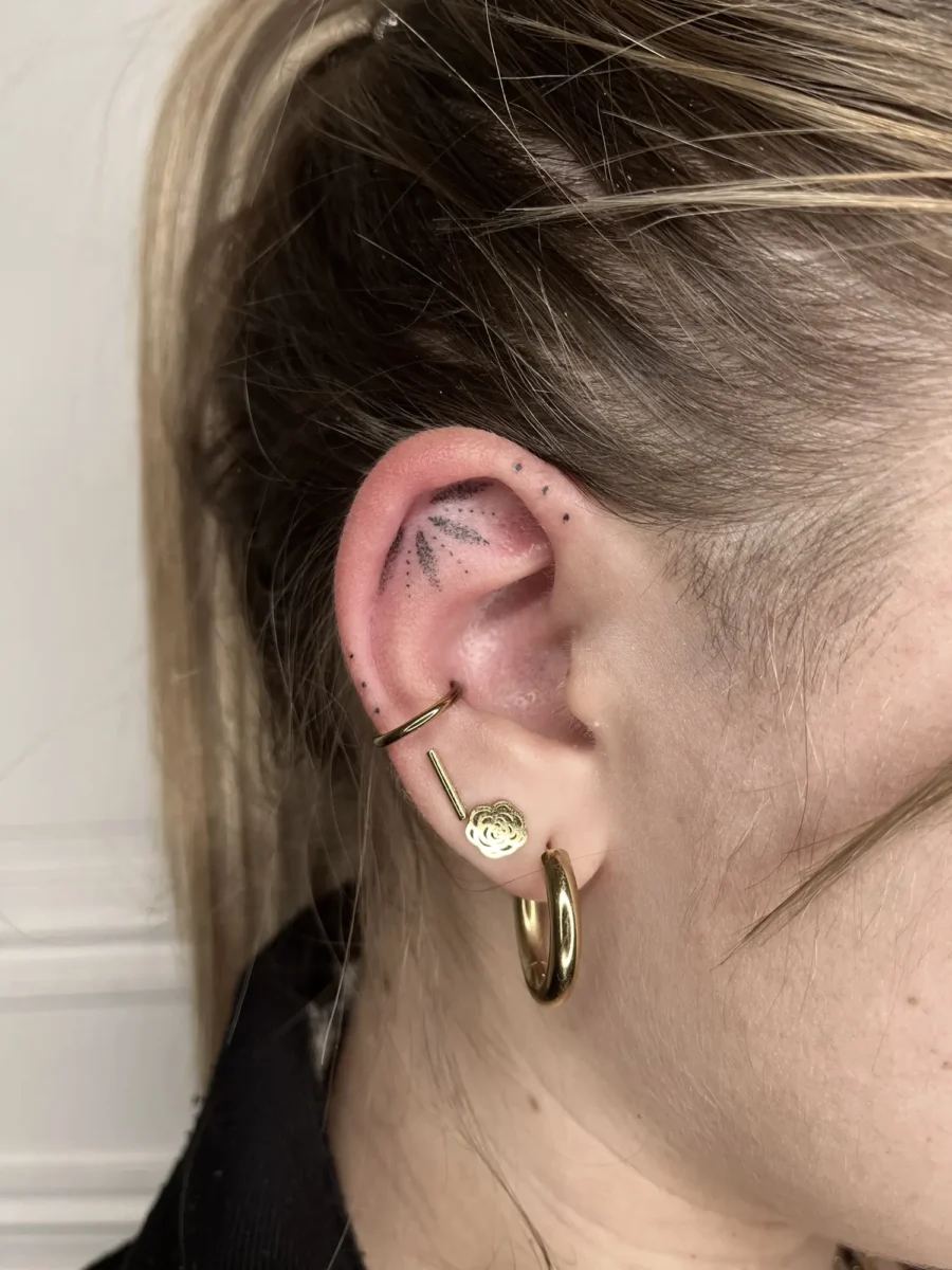 Tatouage handpoke ornemental autour de l’oreille, réalisé par Flori Green
