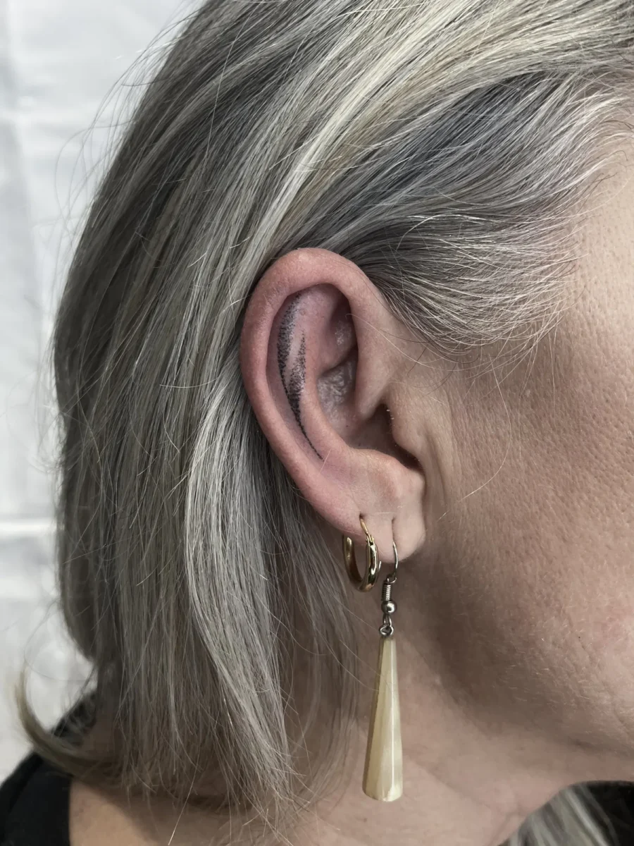 Tatouage handpoke ornemental autour de l’oreille, réalisé par Flori Green