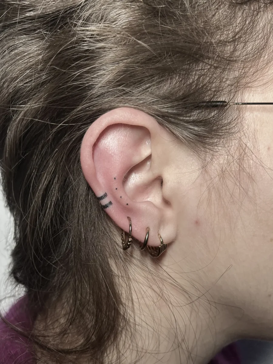 Tatouage handpoke ornemental autour de l’oreille, réalisé par Flori Green