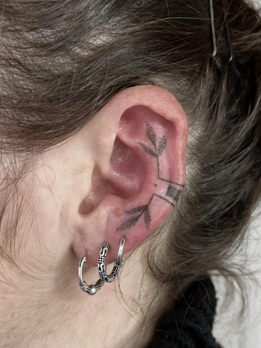 Tatouage handpoke ornemental autour de l’oreille, réalisé par Flori Green