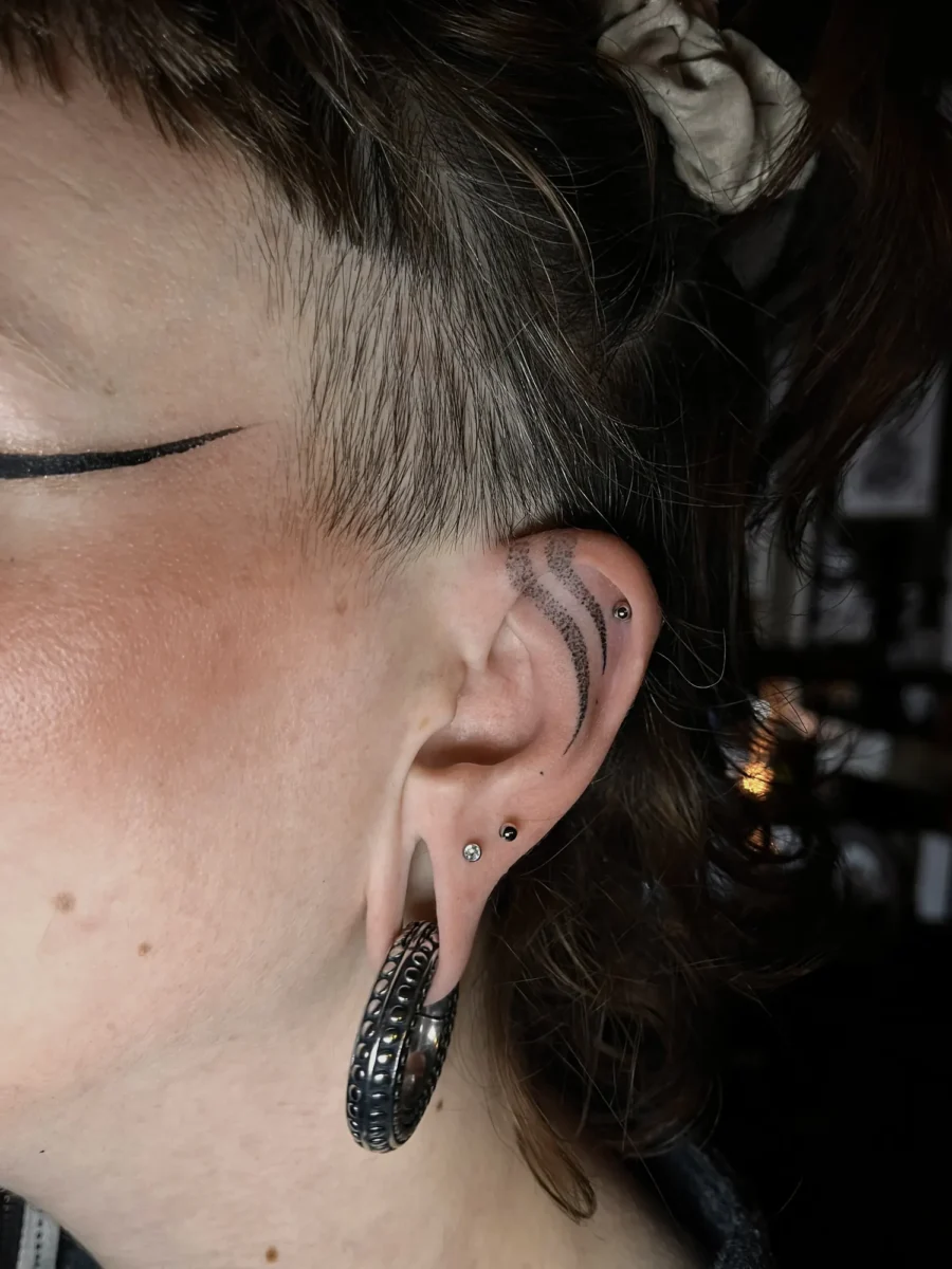 Tatouage handpoke ornemental autour de l’oreille, réalisé par Flori Green