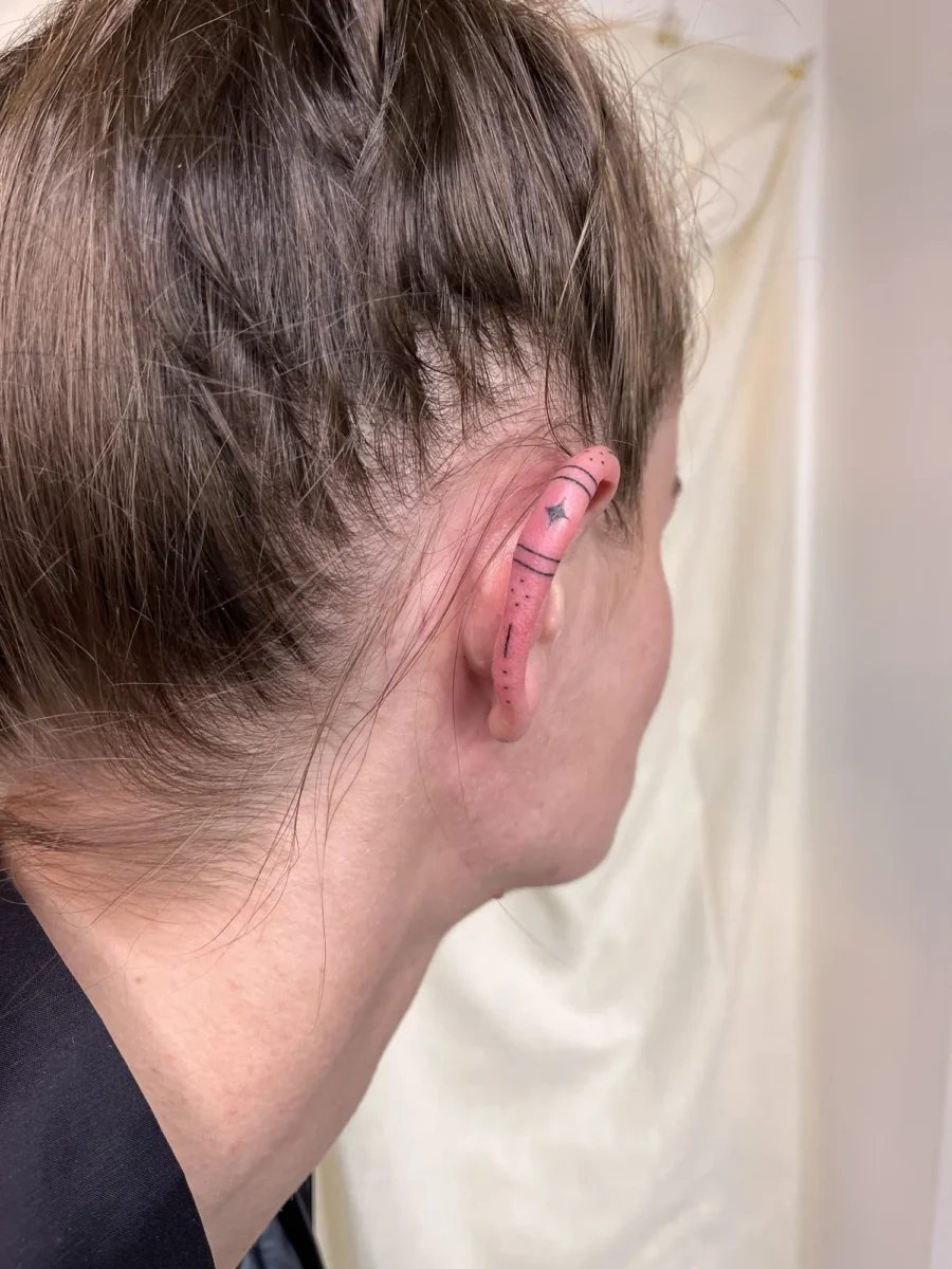 Tatouage handpoke ornemental autour de l’oreille, réalisé par Flori Green