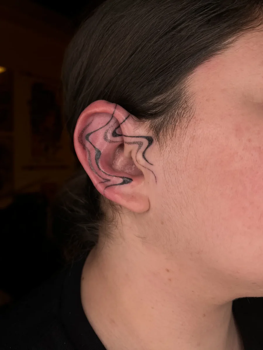 Tatouage handpoke ornemental autour de l’oreille, réalisé par Flori Green