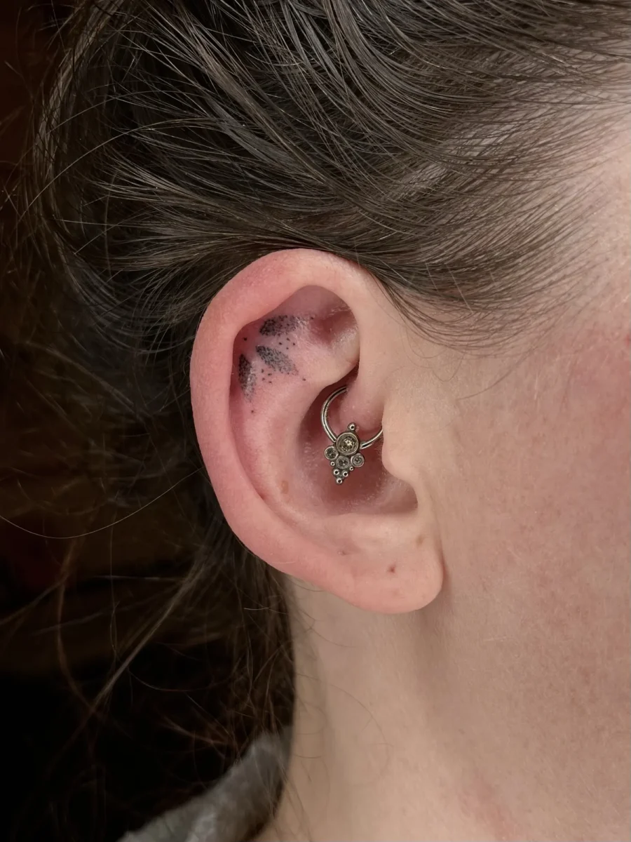 Tatouage handpoke ornemental autour de l’oreille, réalisé par Flori Green