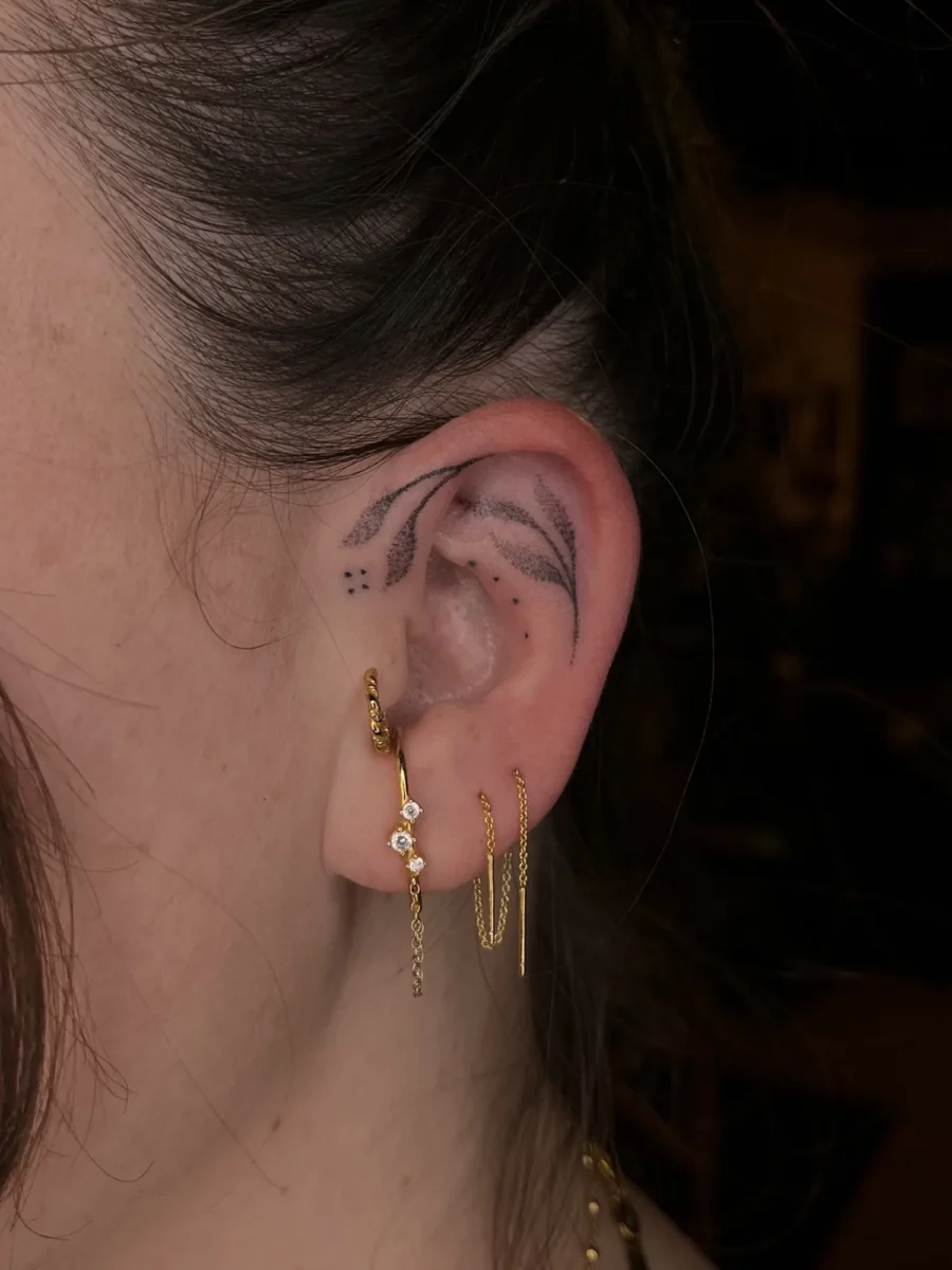 Tatouage handpoke ornemental autour de l’oreille, réalisé par Flori Green